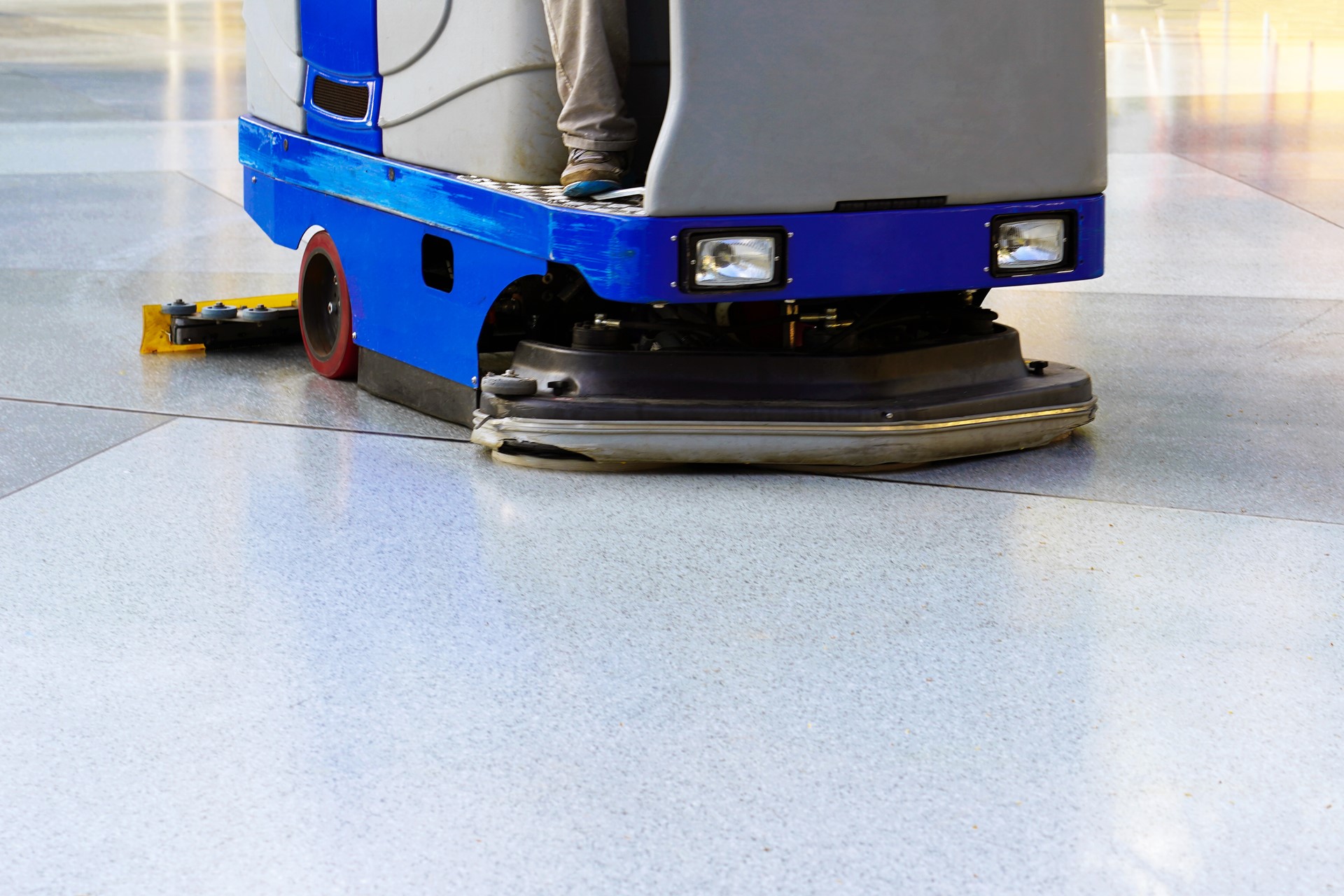 Man driving professional floor cleaning machine at airport or railway station or supermarket. Floor care and cleaning service