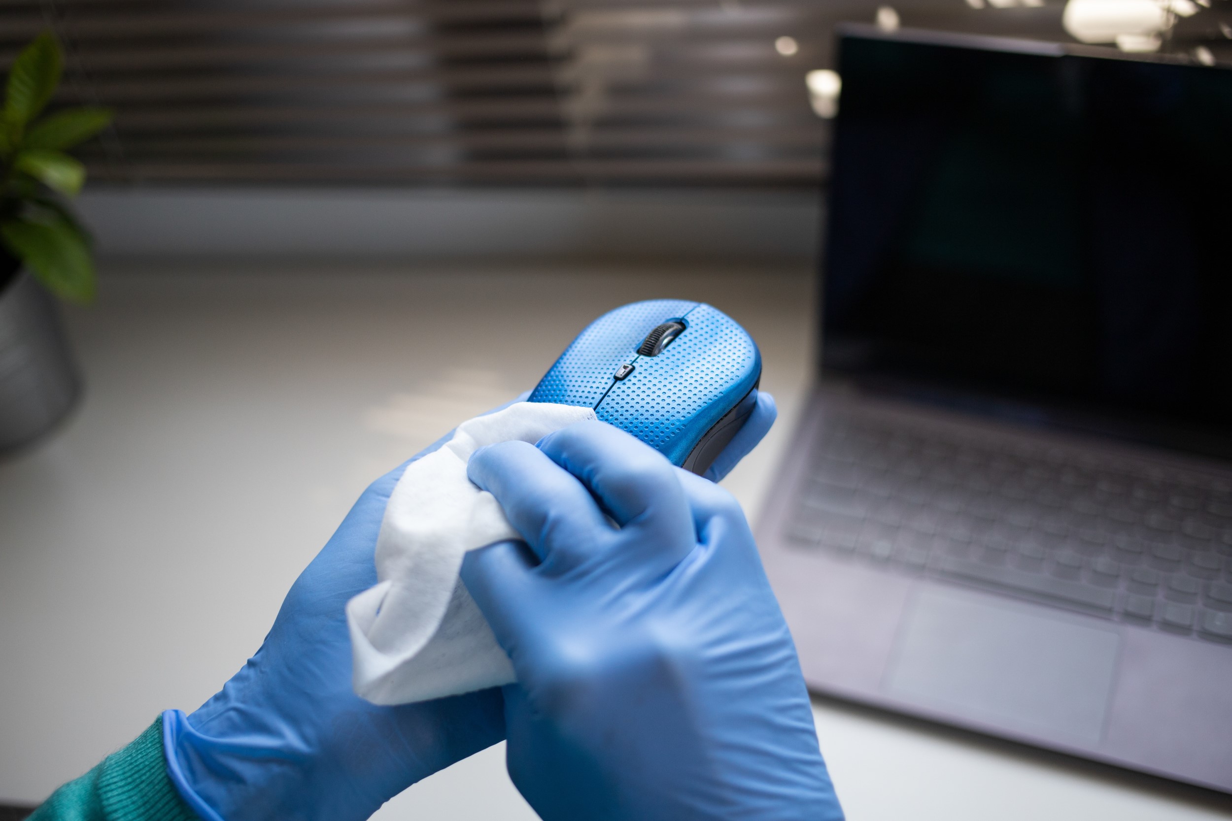 Office sanitizing wipe wiping mouse and mousepad with disinfecting wipes. Coronavirus COVID-19 sanitize cleaning disinfection of work desk.